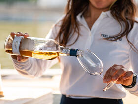 A bartender pours wine into a glass, showcasing the onboard bar experience — perfect for enjoying drinks while cruising.