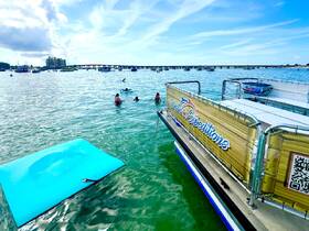 A lively scene with guests enjoying water activities around a pontoon boat, showcasing the fun and excitement of a day on the water.
