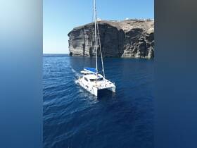 A stunning aerial view of a catamaran sailing through deep blue waters, with a dramatic cliff backdrop, perfect for exploring coastal destinations.