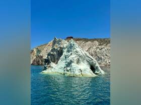 A stunning view of a unique rock formation with swimmers enjoying the clear waters — a perfect highlight of a day on the water.