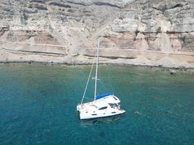 A stunning aerial view of a catamaran anchored near a rocky coastline, with a swimmer enjoying the crystal-clear waters — perfect for a day of adventure and relaxation.
