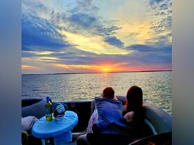 A couple enjoys a romantic sunset view from their pontoon boat, creating a perfect backdrop for memorable moments on the water.
