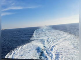 A stunning view of the ocean with a boat's wake trailing behind, showcasing the beauty of cruising on open waters.