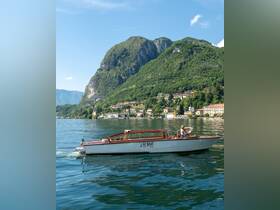 A scenic view of a boat cruising on a tranquil lake, surrounded by stunning mountains — perfect for exploring picturesque landscapes.