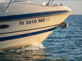 Close-up view of the bow of a boat cutting through the water, showcasing its sleek design and registration number, perfect for highlighting vessel features.