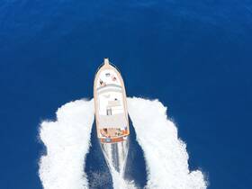 Aerial view of a boat cruising through deep blue waters, showcasing guests enjoying their time on board — perfect for adventure seekers and ocean lovers.