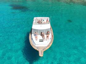 A lively group enjoys a sunny day on a yacht, relaxing and sunbathing in the crystal-clear waters — perfect for summer getaways and fun on the water.