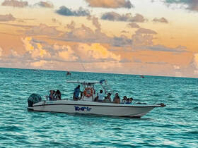 A lively group enjoys a boat ride on the ocean during sunset, capturing the essence of a perfect day on the water.