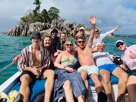 A cheerful group of friends enjoys a fun day on the water, celebrating together on a boat with a stunning island backdrop.