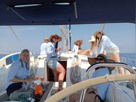 A lively group of friends enjoys a sailing trip, celebrating with cocktails and laughter on a beautiful day at sea.