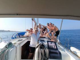 A lively group of friends celebrates aboard a sailboat, enjoying the sun and sea — perfect for unforgettable sailing adventures.