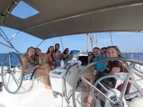 A lively group of friends enjoys drinks and laughter aboard a sailboat, capturing the essence of a fun day on the water.