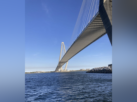 A view of a bridge over water, showcasing its architectural design against a clear blue sky.