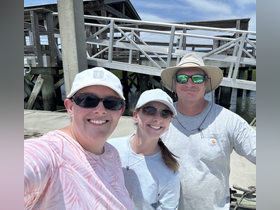 A cheerful group of friends poses for a selfie at the dock, capturing a moment of fun before their boating adventure.