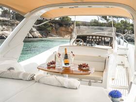 A beautifully arranged interior of a boat featuring a helm and a table set with champagne and fresh fruits, perfect for a luxurious day on the water.