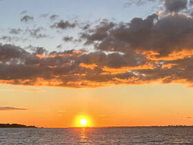 A stunning sunset over the water, casting vibrant colors across the sky — a perfect backdrop for evening boat cruises.