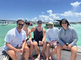 A group of friends enjoys a sunny day on the water, relaxing on a boat with drinks in hand — perfect for a fun day out with friends.