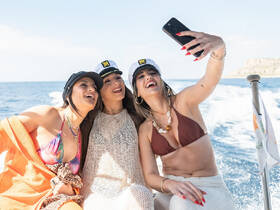 Three friends enjoy a fun moment taking a selfie on a boat, capturing the joy of their day at sea — perfect for memorable outings with friends.