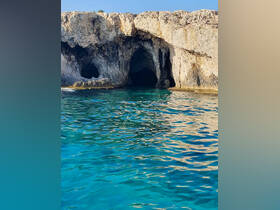 A stunning view of a rocky coastline featuring natural caves, surrounded by crystal-clear turquoise waters — a perfect destination for exploration and adventure.