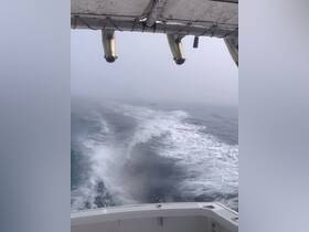 A foggy view from the bow of a boat, showcasing the wake left behind in the water. The unclear visibility adds a mysterious atmosphere to the boating experience.