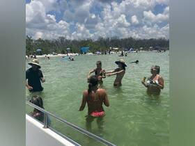 A lively group enjoys a fun day in the water, sipping drinks and celebrating at a beach destination — perfect for summer gatherings and beach parties.