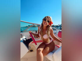 A cheerful young woman poses at the helm of a stylish boat, showcasing the vibrant interior and inviting atmosphere perfect for a day on the water.
