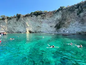 A vibrant scene of swimmers enjoying the crystal-clear waters near stunning cliffs, perfect for a refreshing day of fun and exploration.