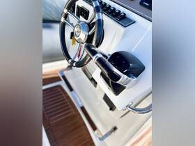 A close-up view of the helm and console of a boat, showcasing the sleek design and controls, perfect for navigating the open waters.