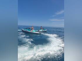 Two individuals enjoy an exhilarating ride on jet skis, creating waves in the clear blue ocean — a perfect snapshot of summer fun on the water.