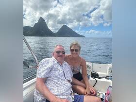 A happy couple enjoys a scenic boat ride with stunning mountain views in the background, perfect for romantic getaways or adventure-filled vacations.