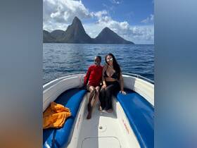 Two friends enjoy a sunny day on a boat with stunning island scenery in the background, perfect for memorable adventures on the water.
