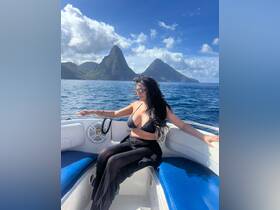 A woman enjoys the stunning view of the Pitons while relaxing on a boat, capturing the essence of a perfect day on the water in St. Lucia.
