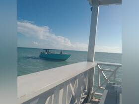 A boat cruises through clear waters, showcasing a lively scene with passengers onboard — perfect for exploring the beautiful coastline.