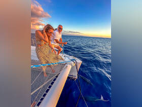 A couple enjoys a beautiful sunset aboard a catamaran, capturing the essence of romance and adventure on the open ocean.