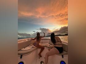 Two friends enjoy a stunning sunset aboard a boat, capturing the moment with a selfie — a perfect backdrop for memorable outings on the water.