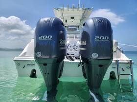 A close-up view of twin Yamaha 200 outboard motors on the back of a boat, showcasing the sleek design against a backdrop of clear turquoise waters.