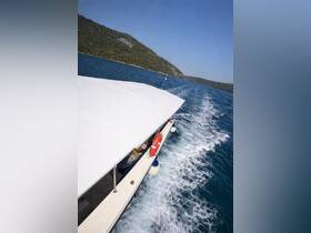 Aerial view of a boat cruising through clear waters, showcasing its sleek design and the beautiful surrounding landscape.