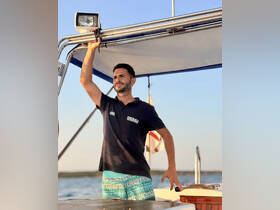 A crew member stands on the deck of a boat, showcasing the vibrant atmosphere of a day on the water. Perfect for highlighting the experience of boating adventures.