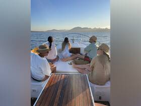 A group of friends enjoys a scenic boat ride, taking in the beautiful views of the coastline at sunset — perfect for relaxation and bonding on the water.