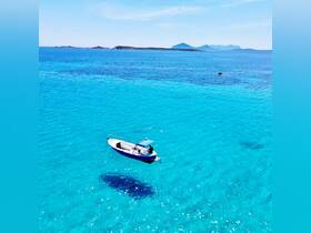 Aerial view of a small boat cruising through crystal-clear turquoise waters, surrounded by stunning island scenery — perfect for exploring hidden gems.