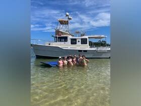 A lively group of friends enjoys a sunny day swimming near their boat, creating unforgettable memories at the beach.