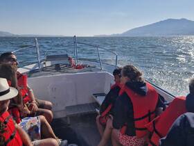 A group of friends enjoys a boat ride, wearing life jackets, as they cruise through scenic waters — perfect for adventure seekers and family outings.