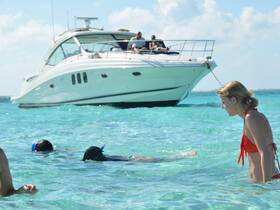 A group enjoys snorkeling in crystal-clear waters while a luxurious boat anchors nearby, creating the perfect backdrop for a fun day on the water.