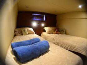 Cozy interior cabin of a boat featuring two twin beds, decorative pillows, and plush toys, perfect for comfortable overnight stays on the water.