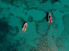 Aerial view of two boats navigating through crystal-clear turquoise waters, showcasing the beauty of a perfect day on the water.