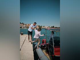 A lively moment captured as two friends prepare to board a boat from the dock, showcasing the excitement of a day on the water.