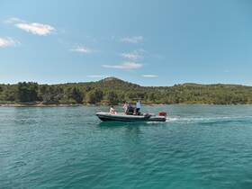 A scenic view of a boat cruising through clear waters, with passengers enjoying the ride against a backdrop of lush greenery and hills.