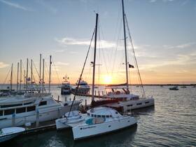 A stunning sunset view of various boats docked at the marina, featuring a prominent catamaran named 'Good Medicine' — perfect for showcasing the beauty of boating life.