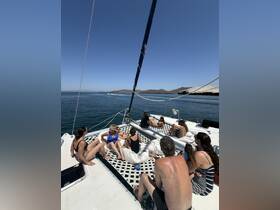 A lively group enjoys a day on a catamaran, relaxing and socializing under the sun — perfect for summer outings and celebrations on the water.