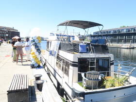 A lively group gathers at the dock beside a decorated boat, perfect for celebrations and events. The colorful balloon display adds a festive touch to the scene.